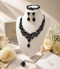 Thumbnail for Black gemstone necklace and earrings on a mannequin bust with white roses and a box in the background.